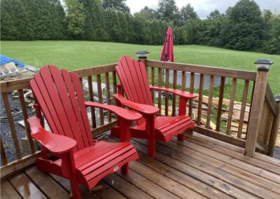 Discover Murphy's Retreat: The Ultimate Multi-Family Cottage Resort in Eastern Ontario - Image of back wooden deck with railings and two red chairs.
